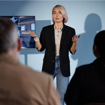 1080-_0000_female-speaker-presenting-at-business-meeting-in-a-2026-01-09-10-05-15-utc